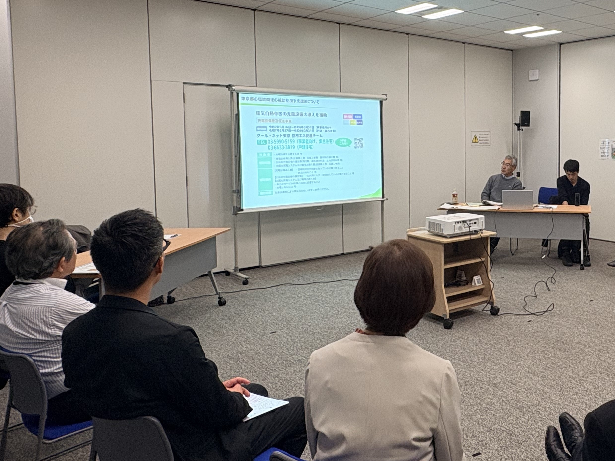 エコまちサークル第三回の様子。奥にスクリーンがある。参加者は車座形式で座っている。
