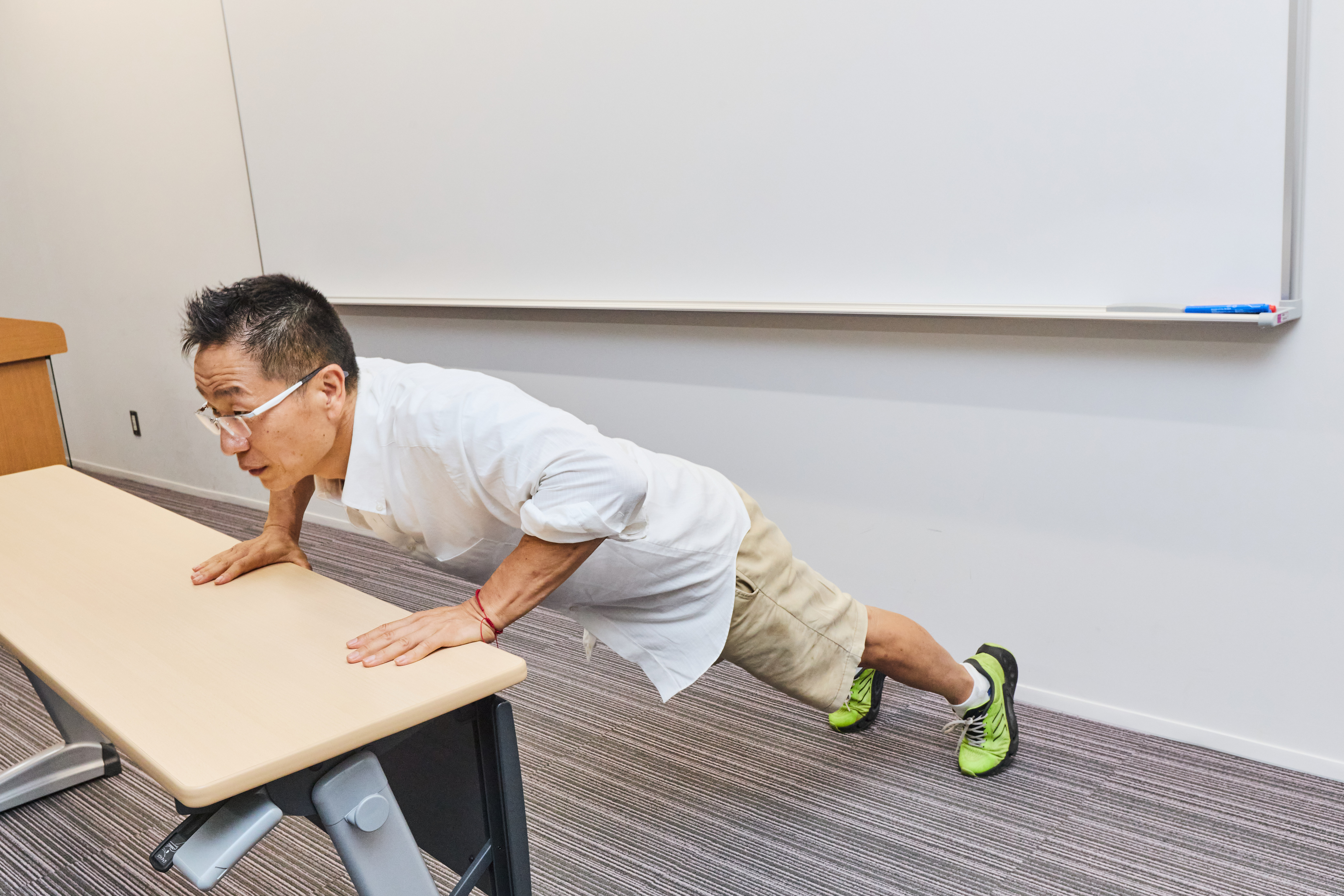 会議室の机で腕立て伏せをする谷本道哉先生
