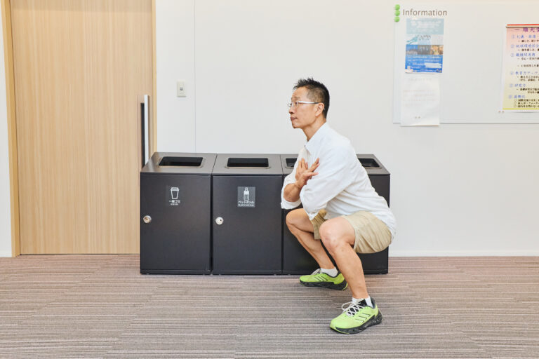 ゴミ箱の前でスクワットをする谷本道哉先生