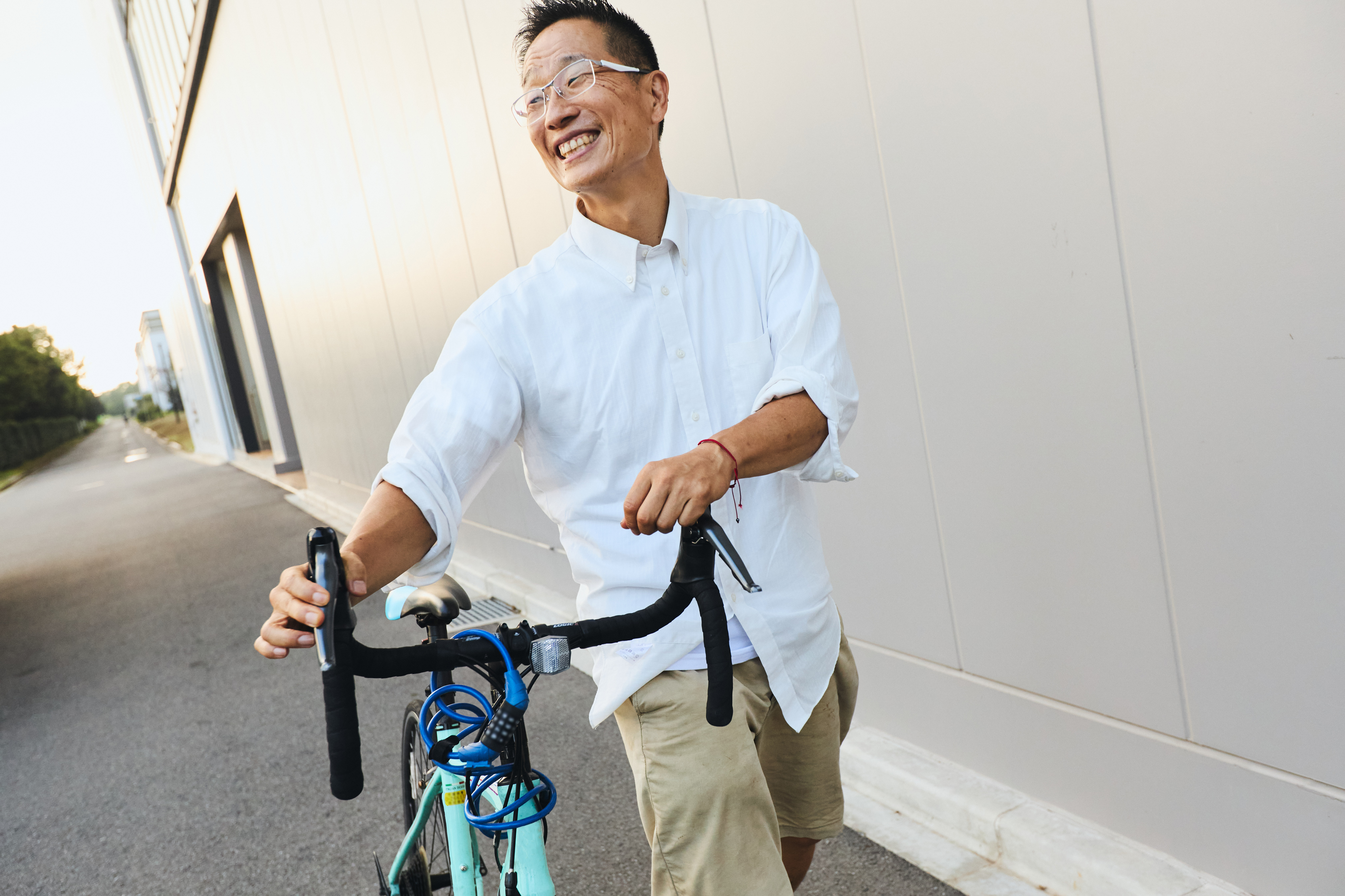 自転車を押しながら、笑顔で話す谷本道哉先生
