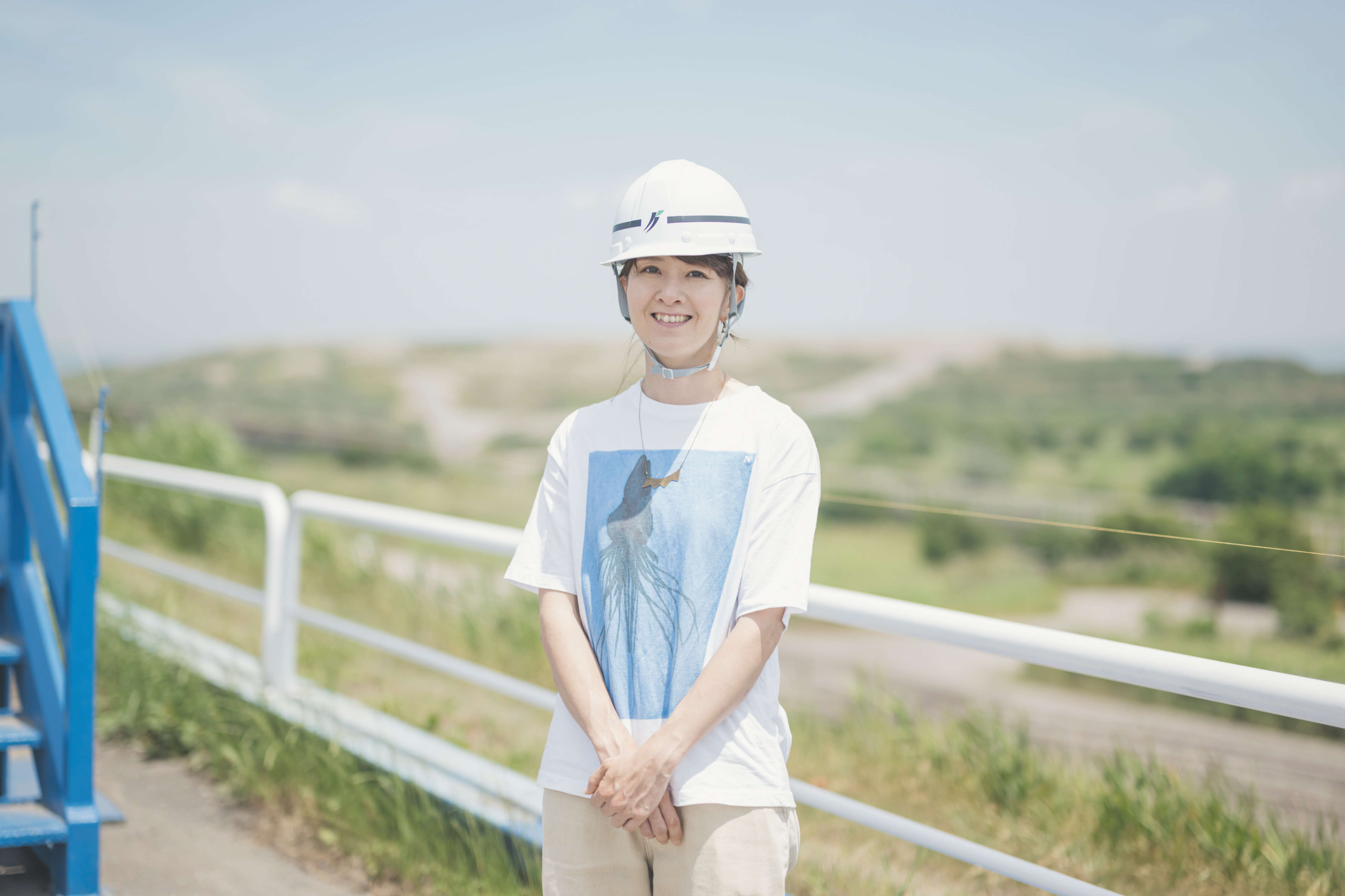 東京都の廃棄物埋立処分を背景に立つ場美術家 富田菜摘さん